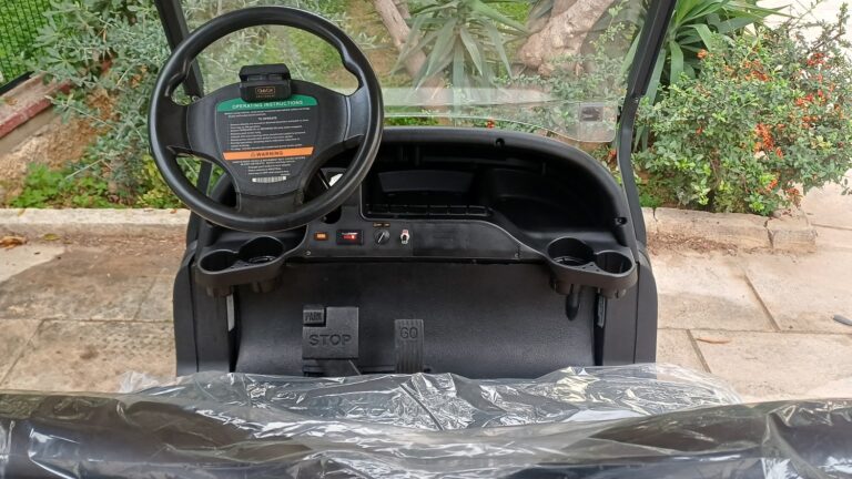 Ταμπλό και θέση οδηγού σε λευκό Club Car Precedent 2015 με μικρό πίσω cargo box, τιμόνι με οδηγίες και πεντάλ STOP και GO